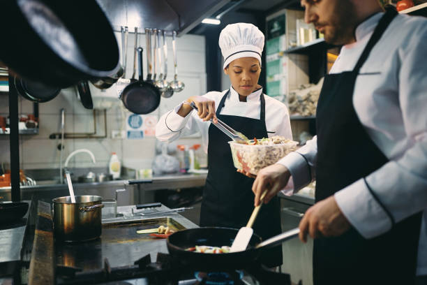 istock Black chef assisting her coworker while preparing meal in a restaurant. 1394055168
