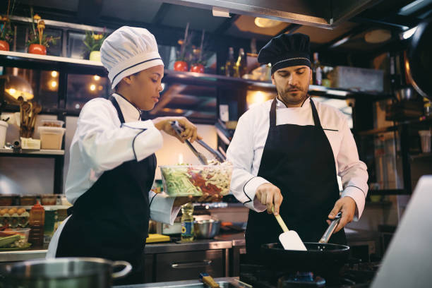 istock Professional cooks cooperating while preparing food in a restaurant. 1394055172