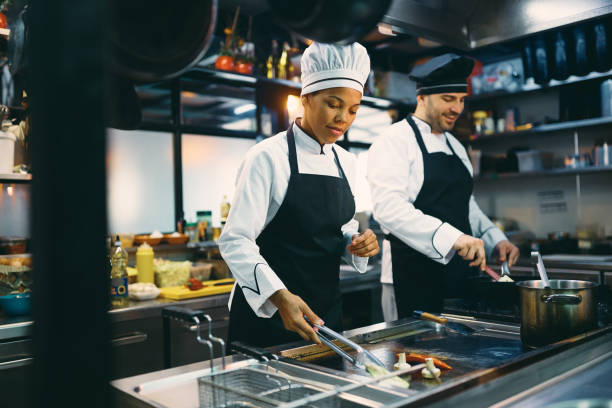 istock Two professional cooks preparing meal in the kitchen at restaurant. 1394055301