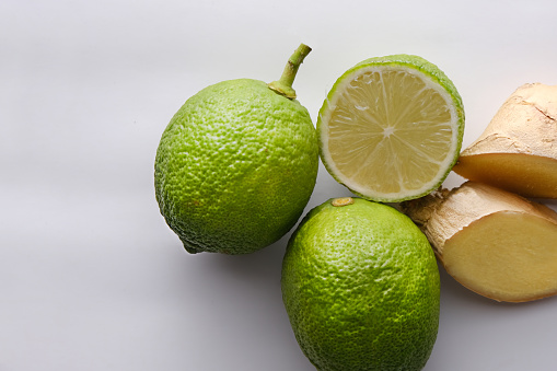 Sliced ginger with lime on white background.