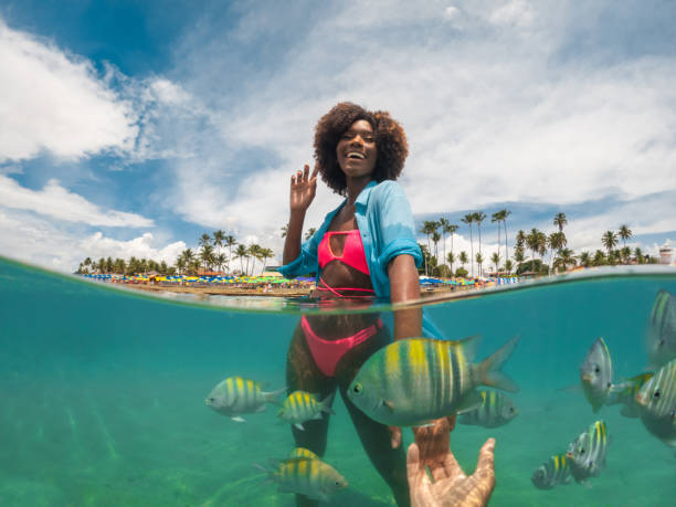 istock Tourists on the beach having fun with the fish 1394057730