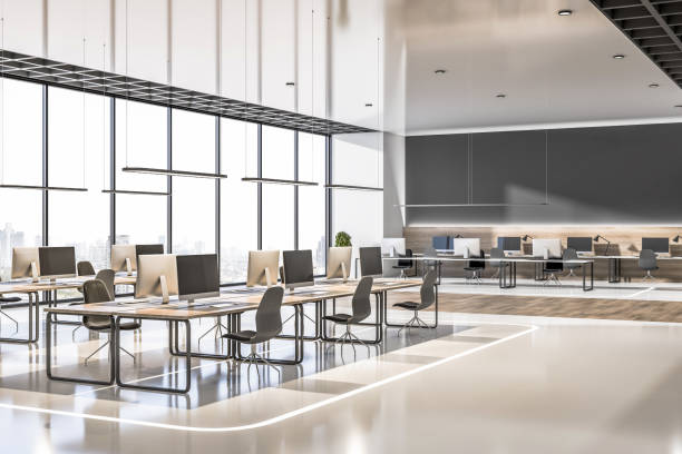 istock Side view on airy modern open space office with eco style interior design, laptops on wooden workspace tables, black chairs, illuminated floor decoration huge glass wall as a window and blank black wall. 3D rendering 1394058109