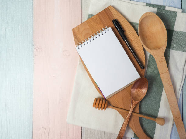 istock Notepad on cutting board with wooden kitchen utensils on the table, food recipes .copy space 1394059904