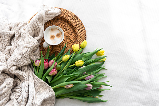 Cozy composition with tulip flowers and coffee on a white background, top view, spring background.
