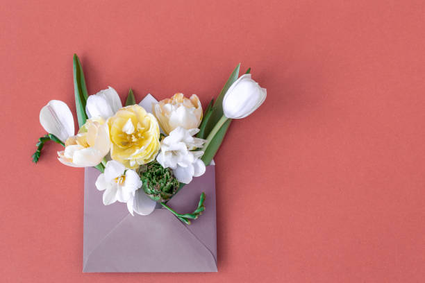 istock Flowers in an envelope on a colored background, flat lay. 1394062794