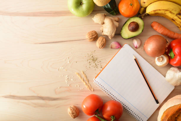 Vegetables on a wooden table and open notepad empty top stock photo