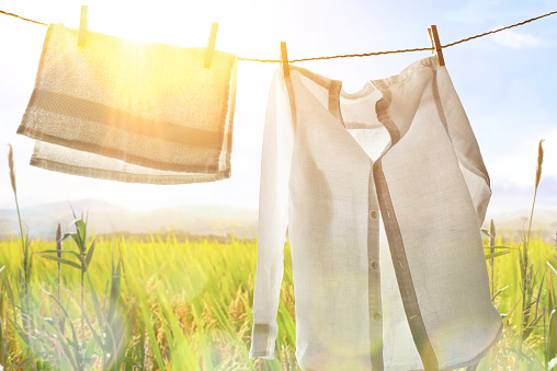 White clothes hanging backlit outdoors with sunny landscape background. Horizontal composition.
