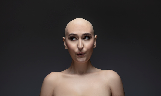 Portrait of happy woman surviving cancer, hair loss from chemotherapy, bald whistling.