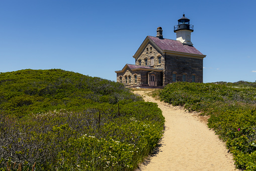 Lighthouse withe lush green and a sand pathway vertical  orientation