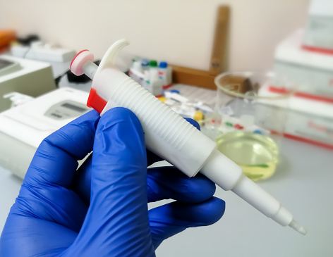 Hand holding micro pipette in laboratory. six ml micro pipette for pcr lab testing.