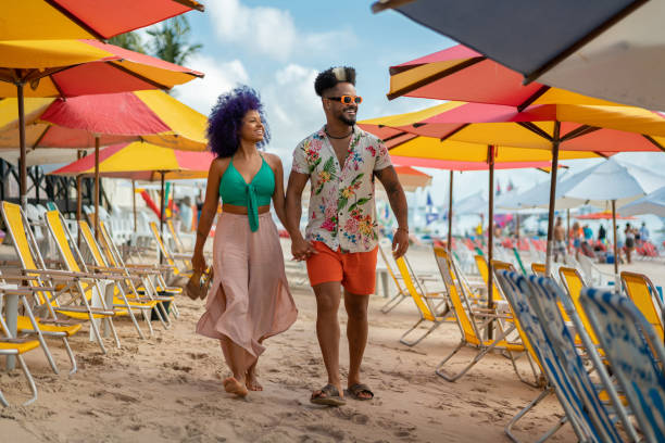 Young afro couple walking hand in hand on the beach stock photo