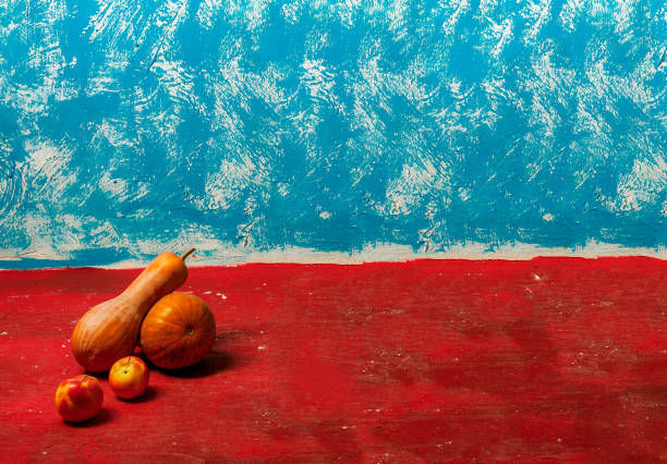 two apples and two pumpkins on a red and blue painted surface with empty space for texts and captions