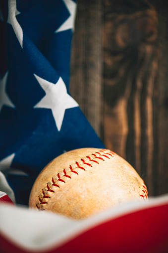 Baseball with an American flag against a rustic wall. Sport background with copy space