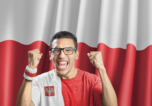 Soccer fan national team of Poland celebrating goal in front of polish flag