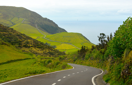 Azores beautiful patchwork landscape with Atlantic ocean view. Asphalt road crossing the valley, Flores island, Açores.
