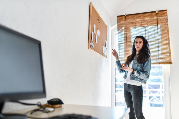 istock Cute Female Office Worker Presenting Tasks For The Day On Noticeboard 1394085997