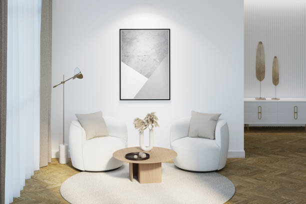 modern interior with an illuminated vertical poster on a white wall. the decor on a coffee table, two modern chairs, a lamp near a curtained window, decor on a nightstand in the background. - accent wall imagens e fotografias de stock