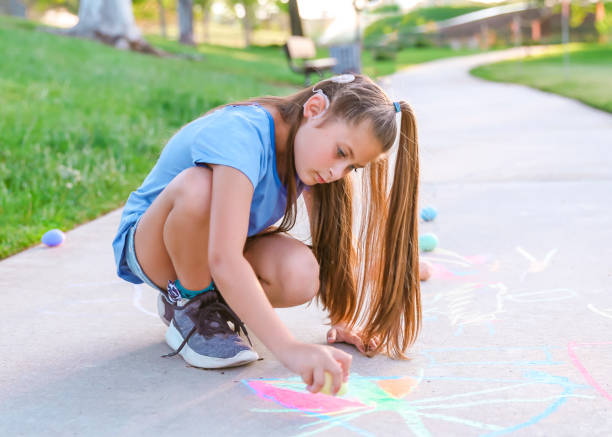 istock Girl with cochlear implant playing with sidewalk chalk 1394101629