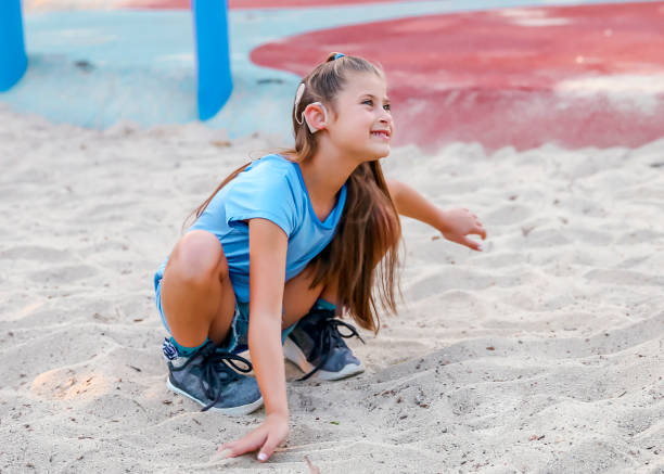 Girl with cochlear implant playing in sand