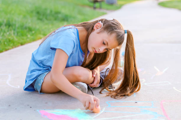 istock Girl with cochlear implant playing with sidewalk chalk 1394101639