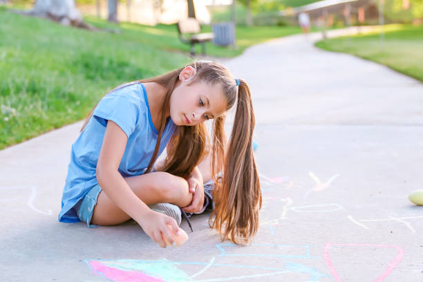 istock Girl with cochlear implant playing with sidewalk chalk 1394101641