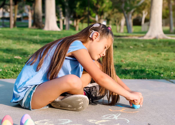 niña con implante coclear jugando con tiza de acera - little girls sidewalk child chalk fotografías e imágenes de stock