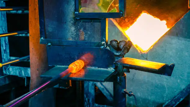 Shaping the hot glass gather during glassblowing process