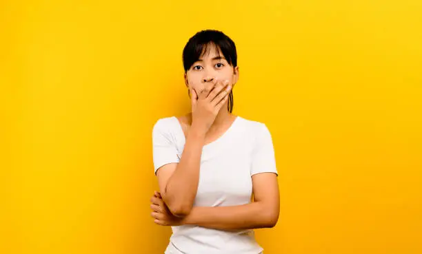 amazing woman Picture of an excited woman standing alone on a yellow background, looking at the camera.