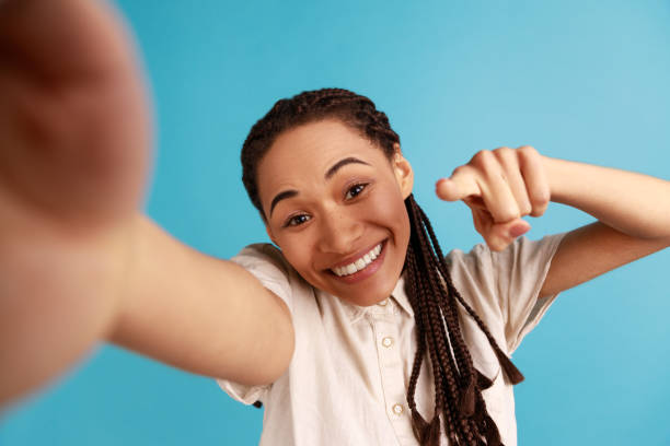 istock Woman has satisfied face expression making selfie, positive emotions, pointing finger to camera, POV 1394110985