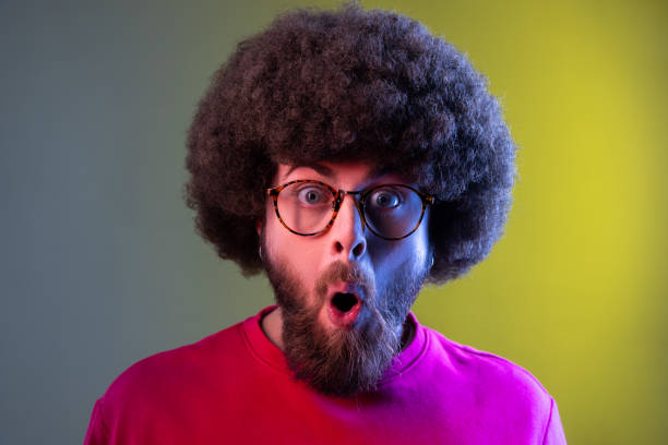 istock Man with Afro hairstyle standing with mouth open in surprise, has shocked expression, unbelievable. 1394111698