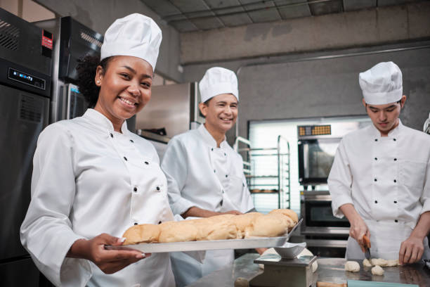 istock Professional female chef with baking bread, cheerful smile in the kitchen. 1394111947