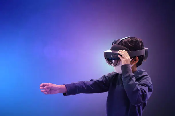 Asian kid boy using metaverse VR virtual reality glasses to digital technology metaverse game.