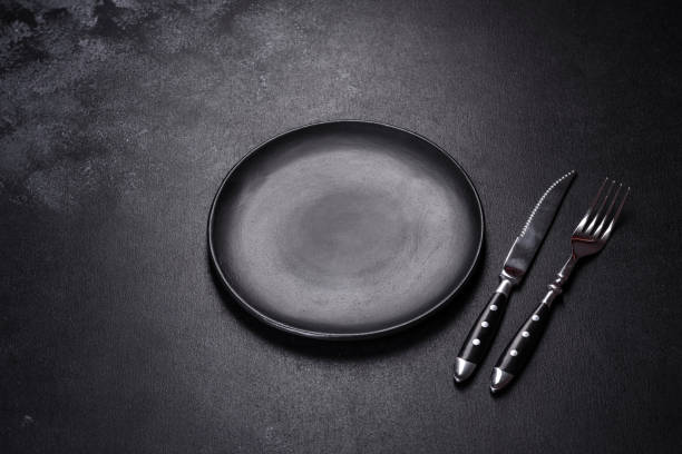 istock Empty round black plate on dark moody black background with copy space 1394118386