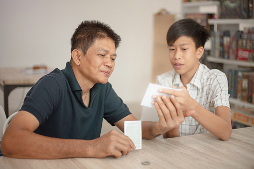 Asian son teaching his father to play board games