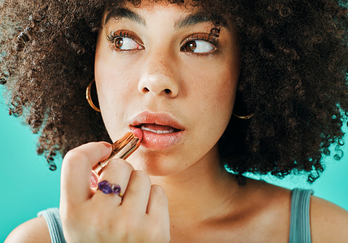 Afro model putting lipstick in the studio