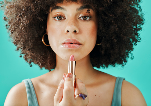Afro model holding lipstick in the studio