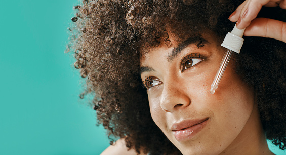 Closeup afro model putting serum on her face in the studio