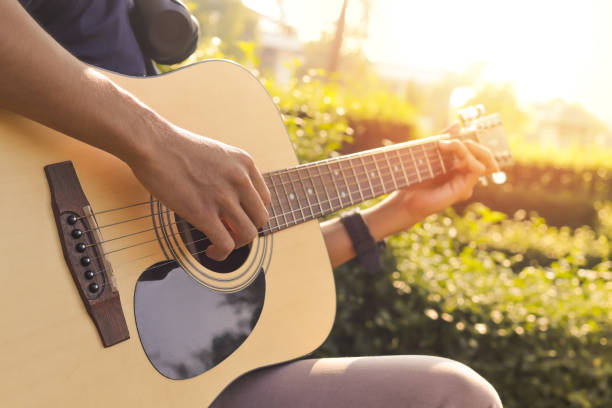 istock male hand playing guitar against sunlight in the park 1394136281