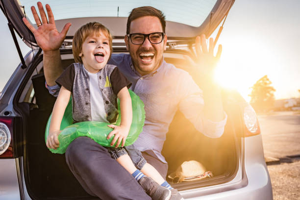 istock Playful single father and son making faces in the car trunk at sunset. 1394136828