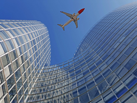 Plane flying over modern office glass skyscrapers