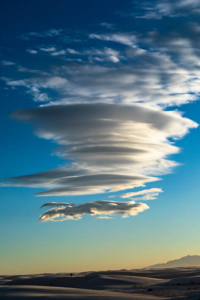 istock white desert sand dunes under a group of dramatic lenticular shape clouds and blue sky. 1394139465