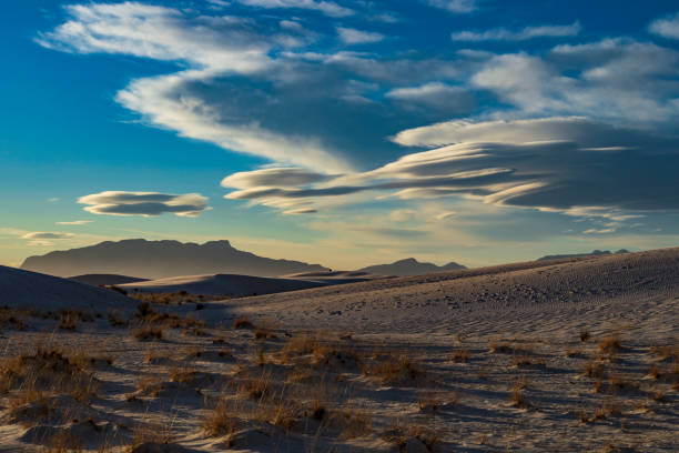 istock white desert sand dunes under a group of dramatic lenticular shape clouds and blue sky. 1394139468