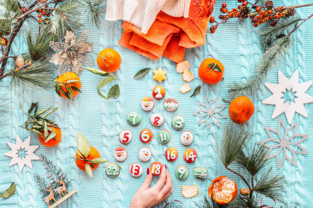 femme fabriquant à la main un sapin de noël avec biscuit pour le calendrier de l’avent sur une couverture tricotée bleue avec mandarines, pull orange et branches de sapin, vue de dessus. - advent calendar advent christmas tree christmas photos et images de collection