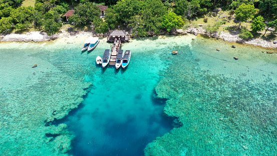 Touristic boats at the pier in blue sea on Menjangan island. Aerial view.