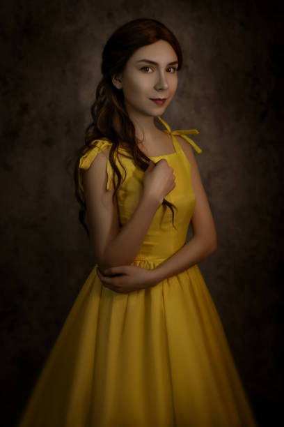 Pretty woman in the yellow long dress closeup with red rose in her hands. Beauty and the beast cosplay Pretty woman in the yellow long dress closeup with red rose in her hands. Beauty and the beast cosplay. beauty and beast rose stock pictures, royalty-free photos & images