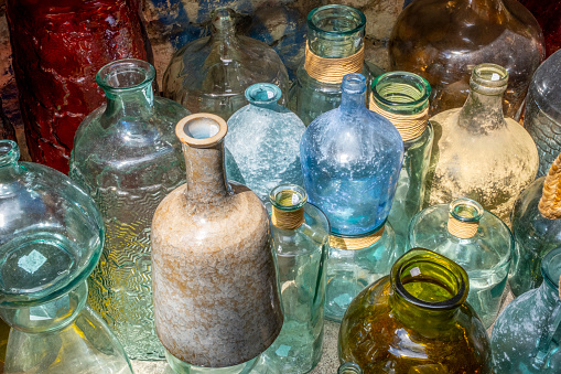 A row of old blue/green bottles rest on the window sill of an old house on Cape Cod