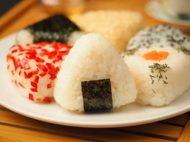Onigiri of various shapes and fillings on a plate. Close-up food photo. Japanese rice ball.