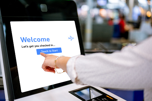 Female traveler using the check-in machine at the airport getting the boarding pass. Individuals Business Travelling Concept.