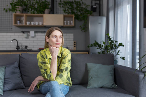 istock Pensive middle aged woman sitting at home on sofa thinking 1394158816