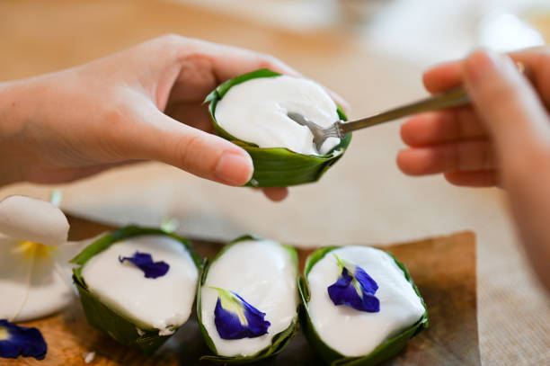 Female eating Thai pudding topping with coconut cream sauce.